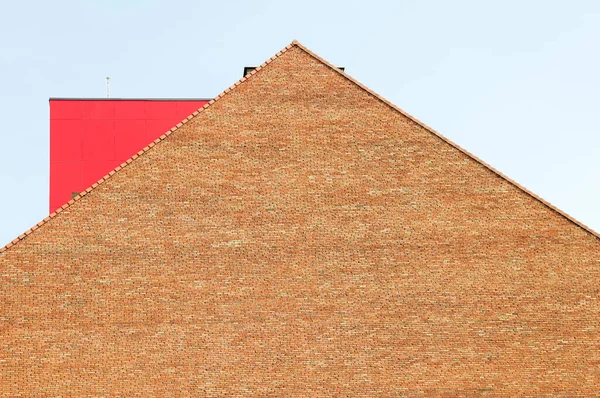 Red brick building top with a red metal object on the roof.