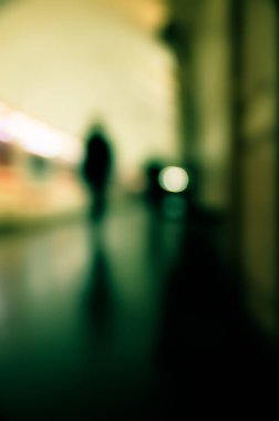 Motion blur image of a subway platform with human silhouettes.
