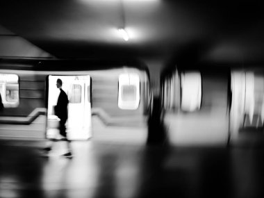 Trenle ve yolcularla metronun siyah ve beyaz hareket bulanık görüntüsü.