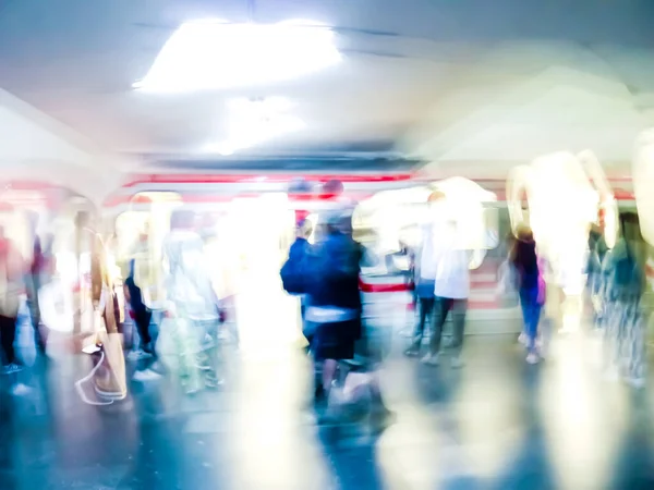 Lens blur image of a subway with moving human silhouettes and a train. Motion blur image of people.