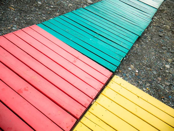 stock image Colorful wooden path on a stony beach.