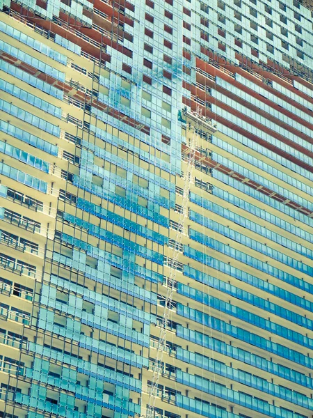 Full frame image of a futuristic building with mirrored aqua blue exterior.