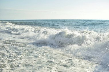 Denizde büyük dalgalar. Parlak sabah güneşinin altında su sıçratan güzel deniz..