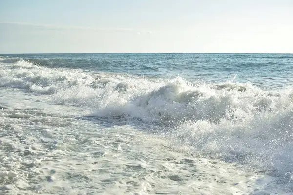 Denizde büyük dalgalar. Parlak sabah güneşinin altında su sıçratan güzel deniz..