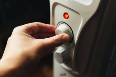 Evdeki elektrikli ısıtıcıyı ayarlayan adam. Soğuk kış, ekonomik kriz konsepti. Ev ısıtması ve ısı koruması. Yüksek kalite 4k görüntü.