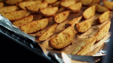 Pişmiş patates dilimleri ve kırsal baharatlar yakın çekim folyoyla kaplanmış bir tepside..