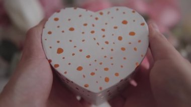 Close-up of a heart-shaped gift box in soft pastel colors against a gorgeous floral background. Perfect for Valentines Day or any romantic occasion. 