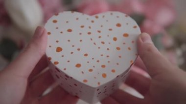 A beautiful heart-shaped gift box, surrounded by a stunning bouquet of pink and white flowers - perfect for Valentines Day or a special occasion.