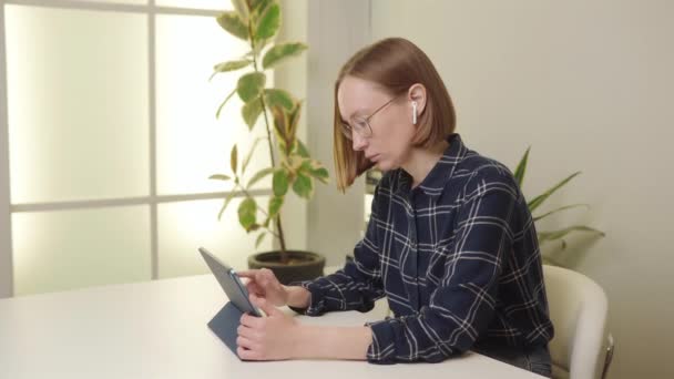 Сосредоточенная Женщина Клетчатой Рубашке Помощью Планшета Белом Столе Офиса Растением — стоковое видео