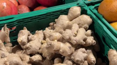 Zencefil kökleri arka planda portakallar olan yeşil bir sandıkta sergileniyor. Yüksek kalite 4k görüntü.