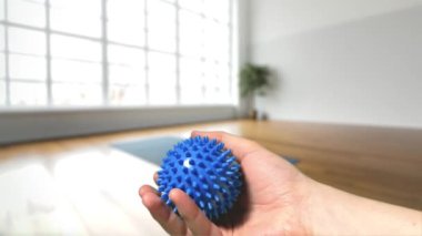 Büyük pencereli ve ahşap zeminli parlak bir odada mavi kauçuk bir masaj topu. Yüksek kalite 4k görüntü.