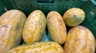 Bir markette ağır çekimde sergilenen yeşil sandıktaki sarı karpuz koleksiyonu. Yüksek kalite 4k görüntü