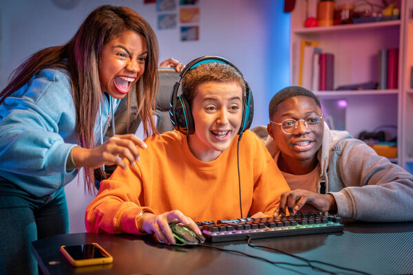 Excited gamers friends playing video games at home laughing while watching how is playing their friend. High quality photo