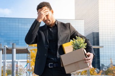 Dismissed sad businessman leaving the office holding cardboard with his personal stuff. Unemployed, crisis, financial, last day at work, fired from job, lay off, losing job. High quality photo clipart