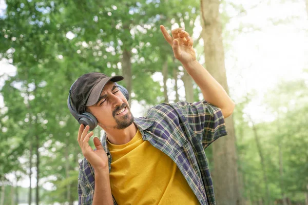 Kulaklık takan, dışarıda müzik dinleyen şarkı söyleyip dans eden bir adam. Mutluluk yaşam tarzı konsepti