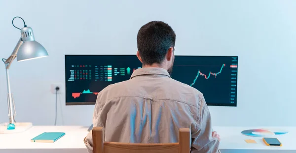 Unrecognizable man looking at computer checking stock exchange market trader graphics. Investor broker analyzing indexes, financial chart. High quality photo