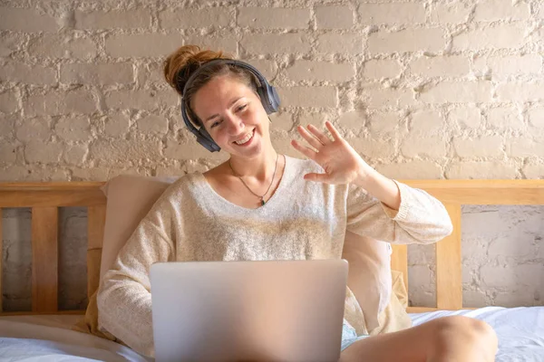 Kulaklıklı bir kadın sanal toplantı yapıyor bilgisayardaki öğretmenle el sıkışarak video görüşmesi yapıyor, online kurslarda çalışıyor ya da özel ders alıyor, uzaktan öğrenci, yüksek kaliteli fotoğraf çekiyor.