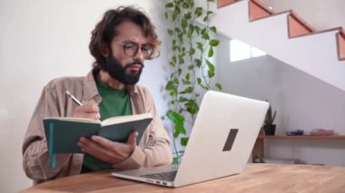 Video konferansına göre uzaktan çalışma. Laptop dinleyerek uzaktan eğitim alan odaklanmış genç bir öğrenci not alıyor. Çevrimiçi sınıf, webinar, ses kursu, e-öğrenim eğitimi, özel ders