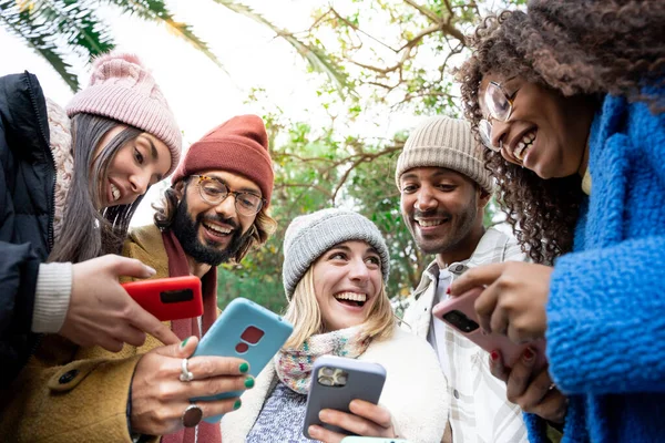 Group of young mixed race friends using cell phones outdoors. Concept of millennial people addicted to technology. Social Media, community, communication, generation Z