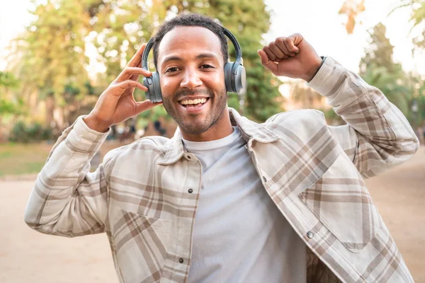  Happy young man listening music and dancing with headphones on the street. Space for text. High quality photo