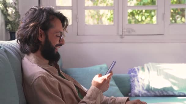 Young Handsome Man Sitting Sofa Using Smartphone Texting Social Network — Wideo stockowe
