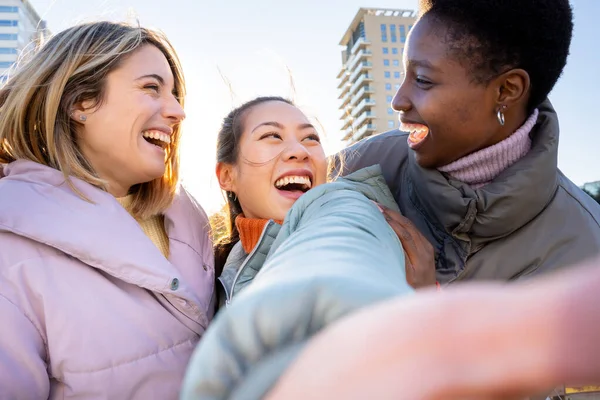 Diverse group of cheerful female friends taking a selfie and having fun together in the street and sharing happiness on social media. Concept of students friendship.