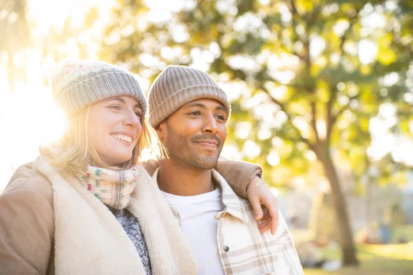 Happy young couple in love smiling and embracing each other while standing outdoors in winter time. Valentines day romantic date. High quality photo