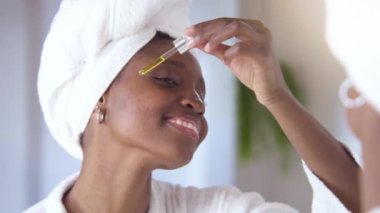 Young black woman applying serum on face with dropper, natural oil skin care morning routine. High quality 4k footage shot on RED camera in slow motion.