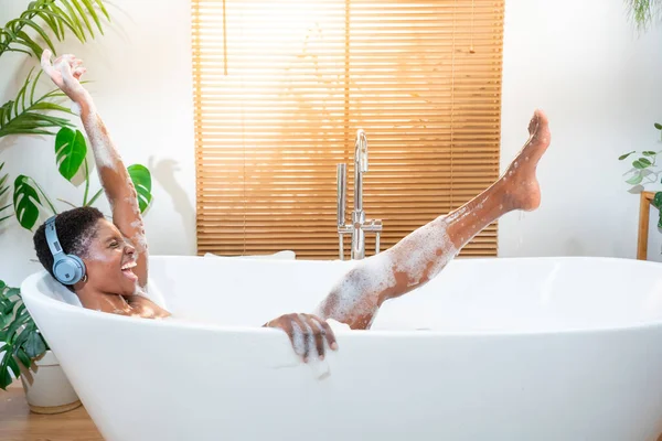 Stress-free weekend, overjoyed, relaxation and self care. Happy woman bathes in a bathtub white foam, listening music and dancing fun emotions. Camera RED slow motion high quality photo