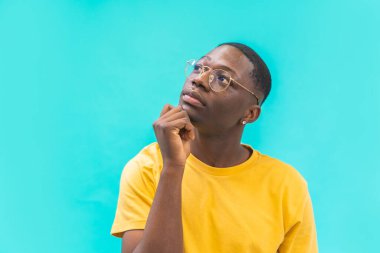 Young doubtful man isolated on background thinking with hand on chin about the good opportunity and try to find solution or right choose. Image with copy space