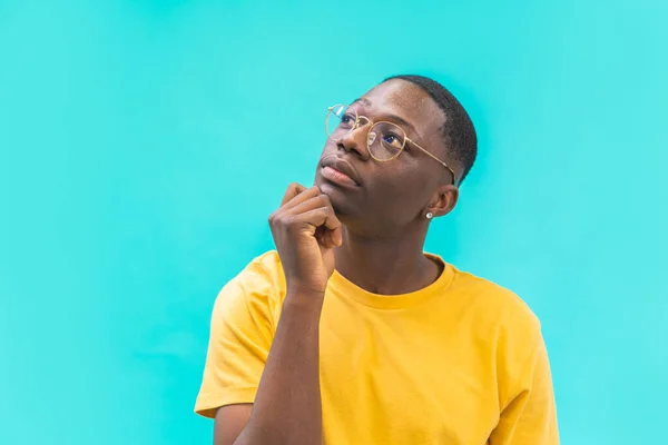 Young doubtful man isolated on background thinking with hand on chin about the good opportunity and try to find solution or right choose. Image with copy space