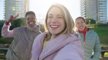 Happy young woman is taking selfie with friends in the city, girl is holding camera and posing, video chat, direct and livestream concept. High quality 4k footage