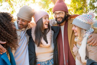 Young group of happy friends people having fun and laughing outdoors. Day of carefree, freedom, laughing together in the park in winter clothing.