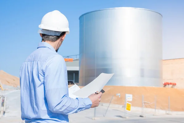 Unrecognizable civil engineer inspecting work with licenses and blueprints, standing outdoors at construction site. Inspector work control. Copy space for text. High quality photo