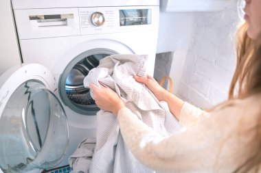 Çamaşır makinesini evde çamaşır makinesine yükleyen tanınmayan bir kadın. Ev işleri, temizlik, görevler, giysi, ev işleri kavramı