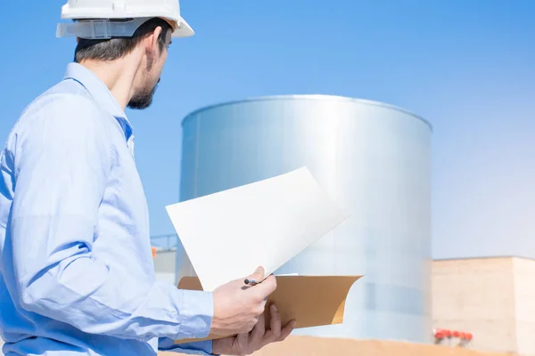 Unrecognizable civil engineer inspecting work at construction site with licenses and blueprints, standing outdoors. Inspector report and control manager. Copy space for text. High quality photo