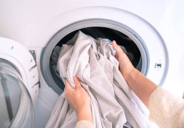 Çamaşır makinesiyle çamaşır yıkayan tanınmayan bir kadın. Çevre temizliği, ev işleri, görevler, giysi, ev işleri ve aile işleri kavramı