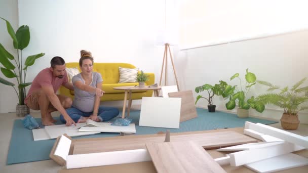 年轻夫妇期待着一个婴儿坐在他们新家组装家具的地板上 新的开始 高质量的照片高质量的Fullhd镜头 — 图库视频影像