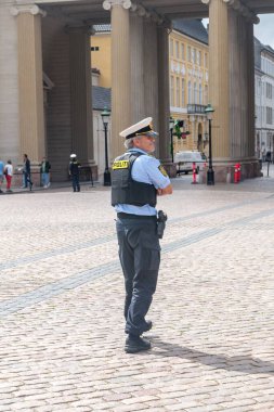 Kopenhag, Danimarka - 26 Temmuz 2022: Polis memuru Amalienborg Meydanı 'nda nöbetçi değişimi sırasında Danimarka Kraliyet Muhafızlarını korudu.