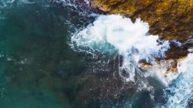Dalgaların yukarıdan aşağı görüntüsü kayalara çarpıyor. Dalgalar kayalıklara çarpıyor.
