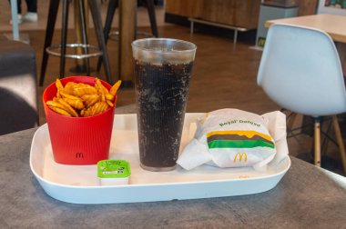 Castets, France - November 19, 2023: McDonald's meal with Royal Deluxe burger, Coca-Cola and potato wedges in plastic box.