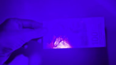 UV ışığında 100 İsviçre Frangı (CHF) banknotuna bak.