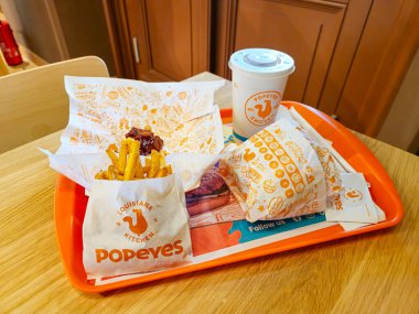 Wroclaw, Polonya - 5 Nisan 2025: Popeyes menüsü Baharatlı Tavuk Sandviçi Deluxe, Büyük patates kızartması, Pepsi ve 3 kalın barbekü fileto.