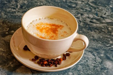 Beyaz fincanda tarçınlı kapuçino kahvesi.