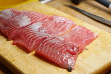 Kesme tahtasında dilimlenmiş çiğ sazan balığı hazırlıyorum.