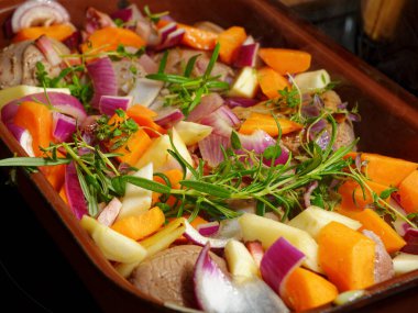 Preparing tasty venison meat with vegetables and herbs in cooking pot