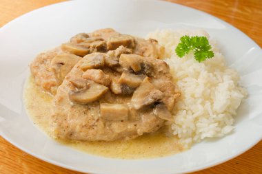 Mantarlı domuz eti sosu ve beyaz tabakta pilav.