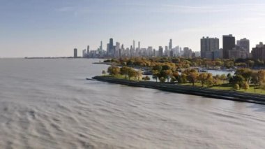 Panning in aerial drone view of the Chicago skyline from Lake Michigan near Belmont harbor on a sunny blue sky fall day.