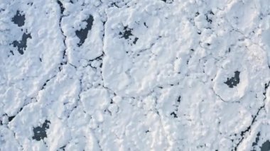 Rising up aerial closeup of snow covering rounded ice chunks floating on Lake Michigan after a Polar Vortex system moved through the Chicago region.