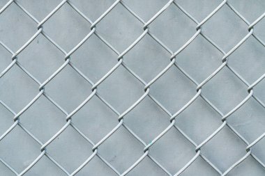 Kırık desenli rüzgar perdesi ya da muşamba arkaplan ile harika bir arkaplan resmi yapan eski beyaz ve gümüş renkli zincirli tel örgülerin yakın plan fotoğrafı..